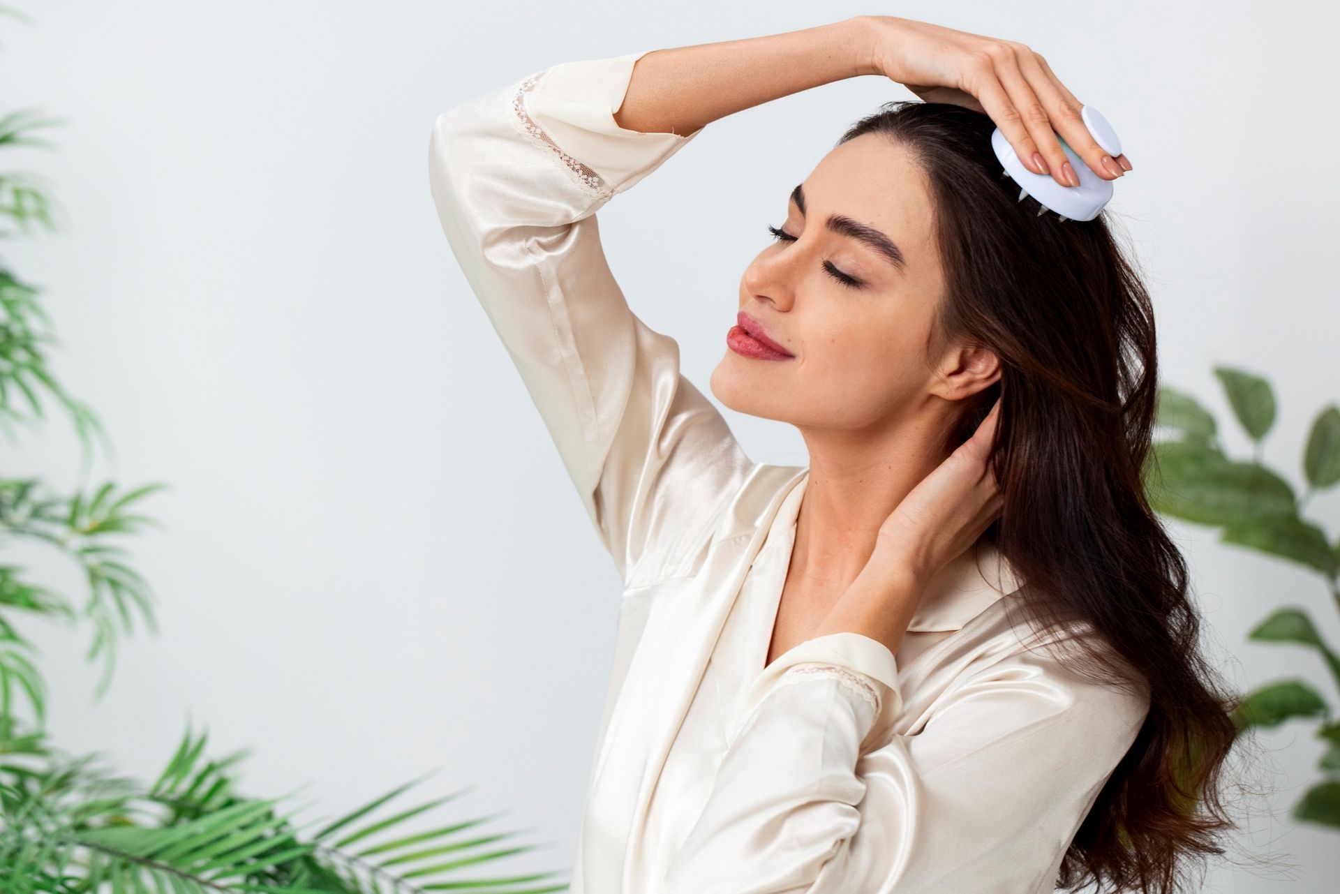 Mujer usando un masajeador de cuero cabelludo, con los ojos cerrados, disfrutando de una experiencia tipo spa.