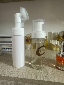 Dos frascos de cosméticos blancos en un estante. Uno es un dispensador de espuma