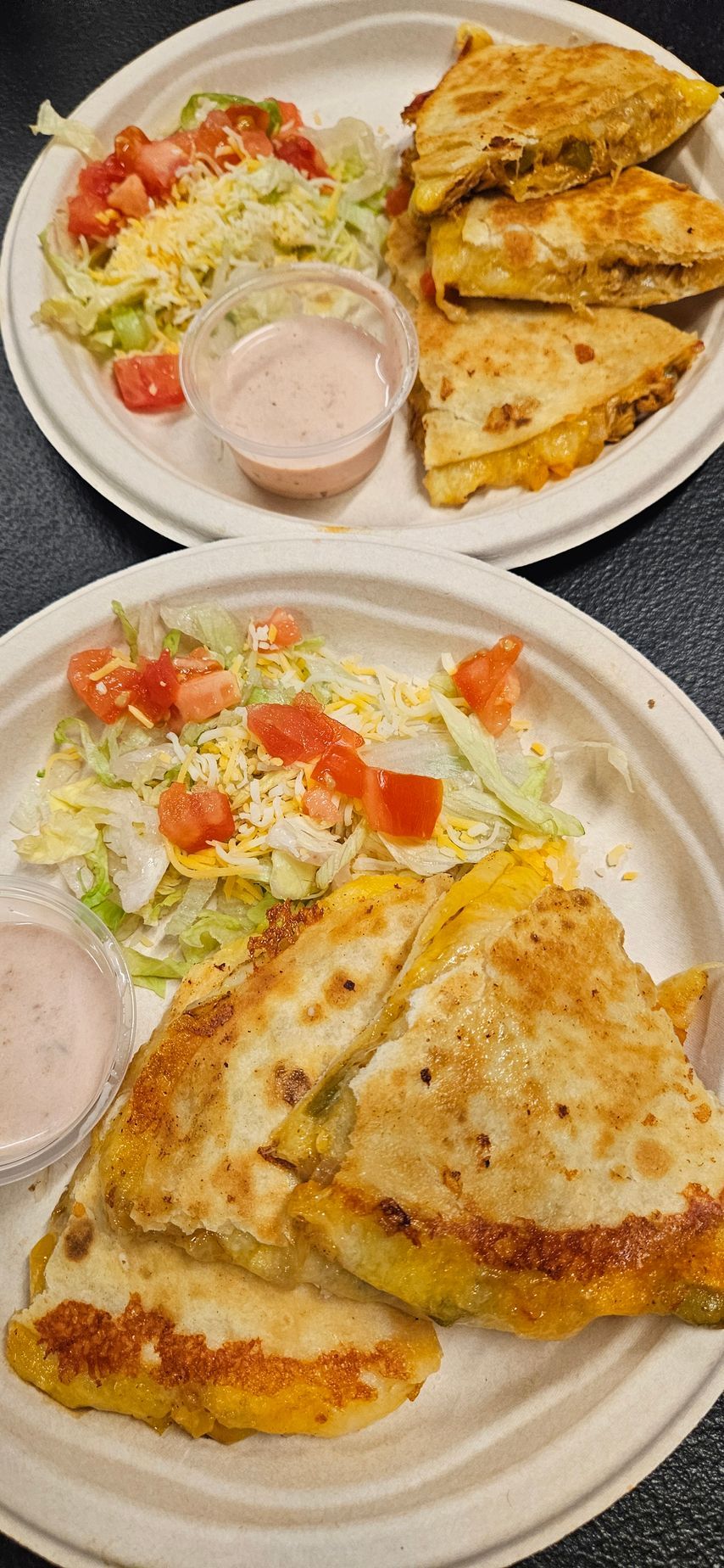 Two plates of quesadillas with salad and sauce.
