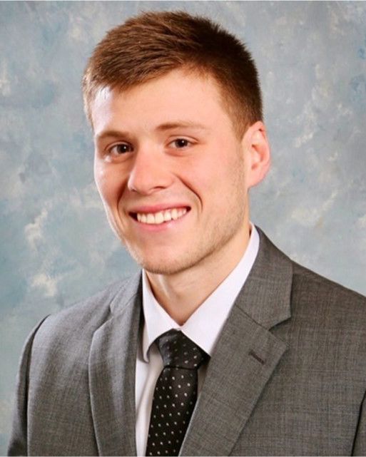 A young man in a suit and tie smiles for the camera