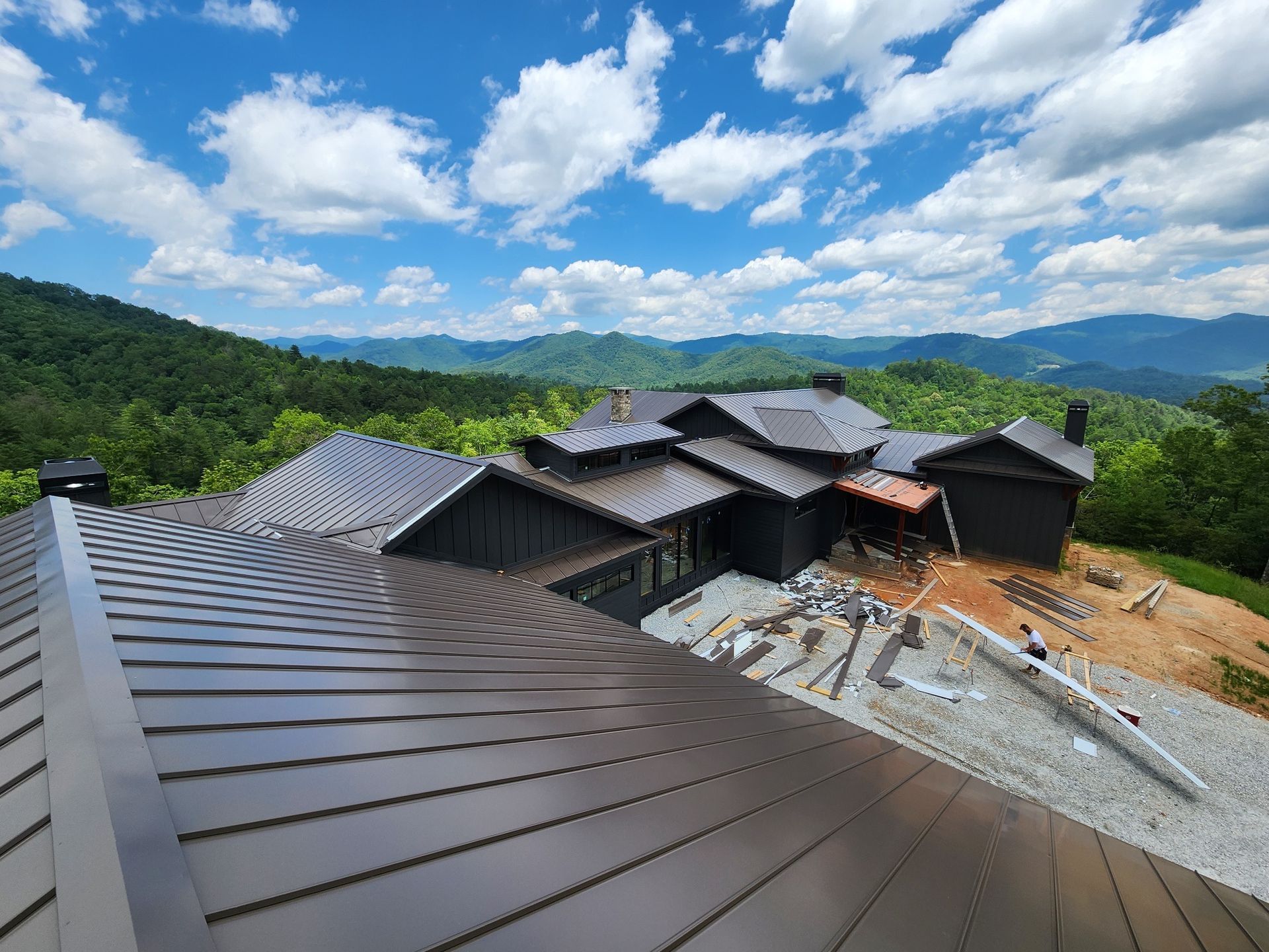 a large house is sitting on top of a hill with mountains in the background .