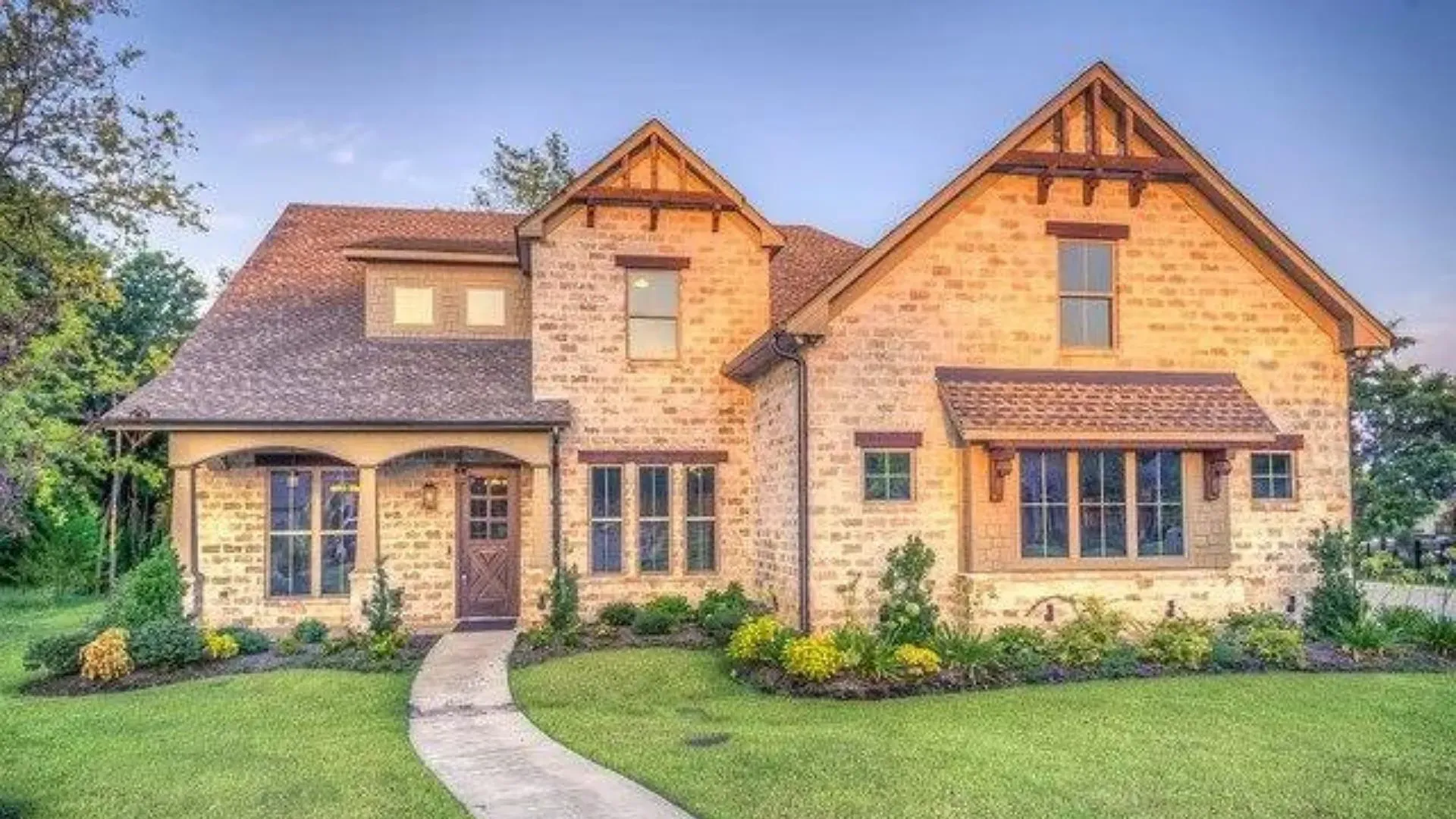 a large brick house with a concrete walkway leading to it