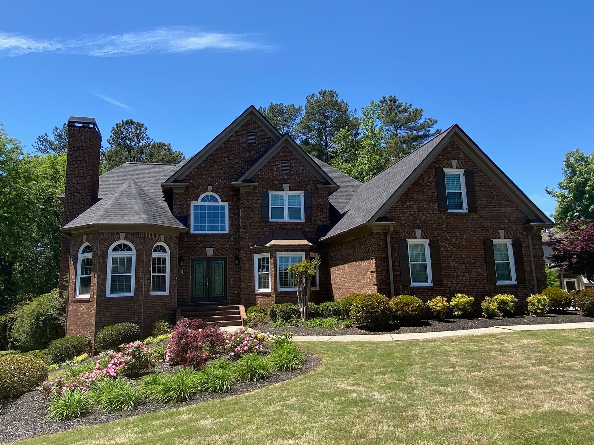 a large brick house with a lush green lawn in front of it