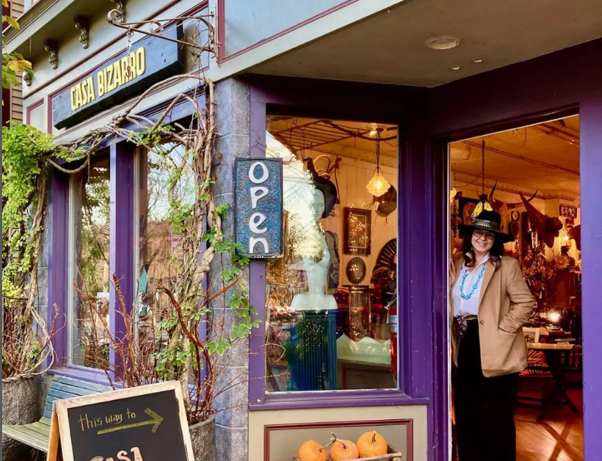 A woman in a hat is standing in front of a purple store.
