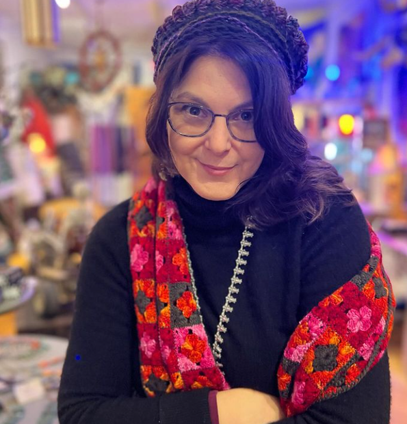 A woman wearing glasses and a scarf is smiling for the camera