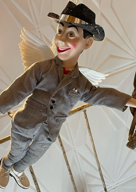 A doll in a suit and hat is flying in the air