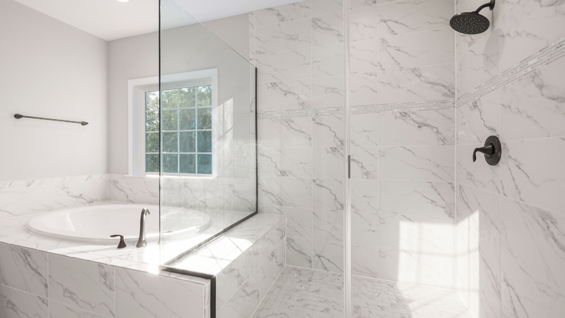 A bathroom with marble walls , a walk in shower , a tub and a window.