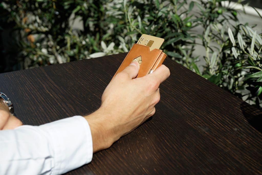 Homem sentado à mesa com com uma carteira da exentri na mão