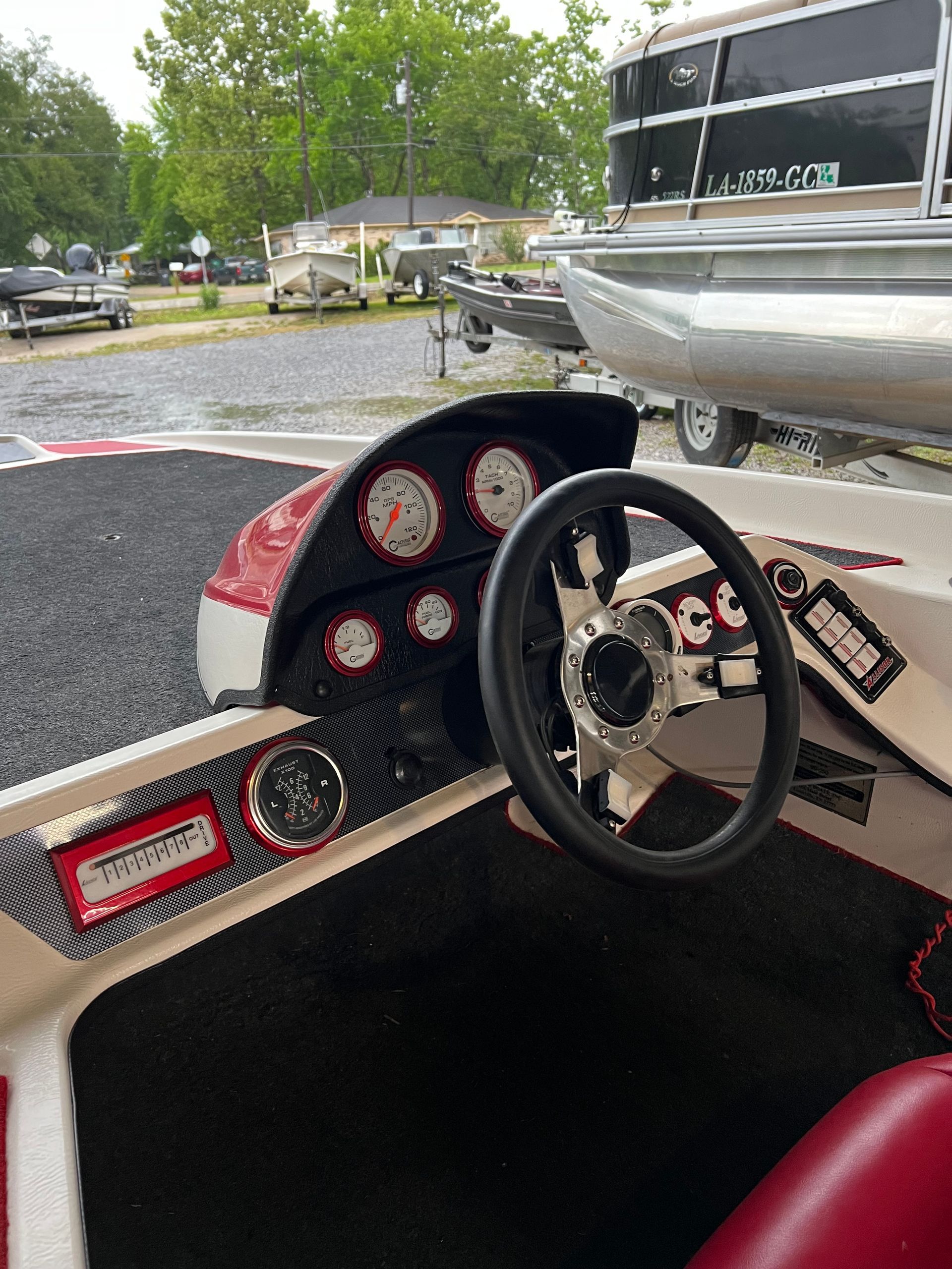 Boat cockpit with steering wheel and gauges. Red, black, and silver.
