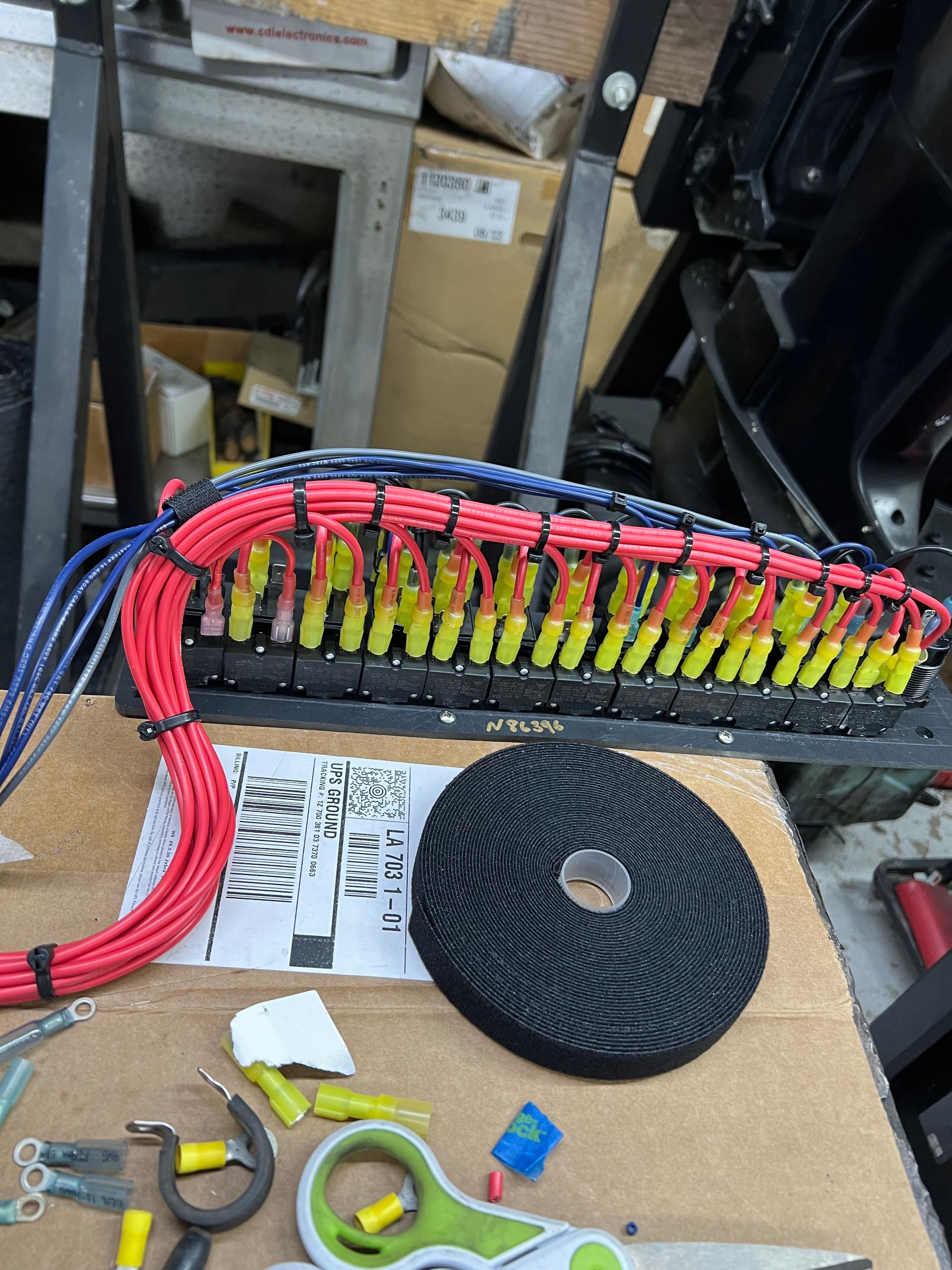 Wiring harness with red and blue wires, yellow connectors, and a black electrical panel.