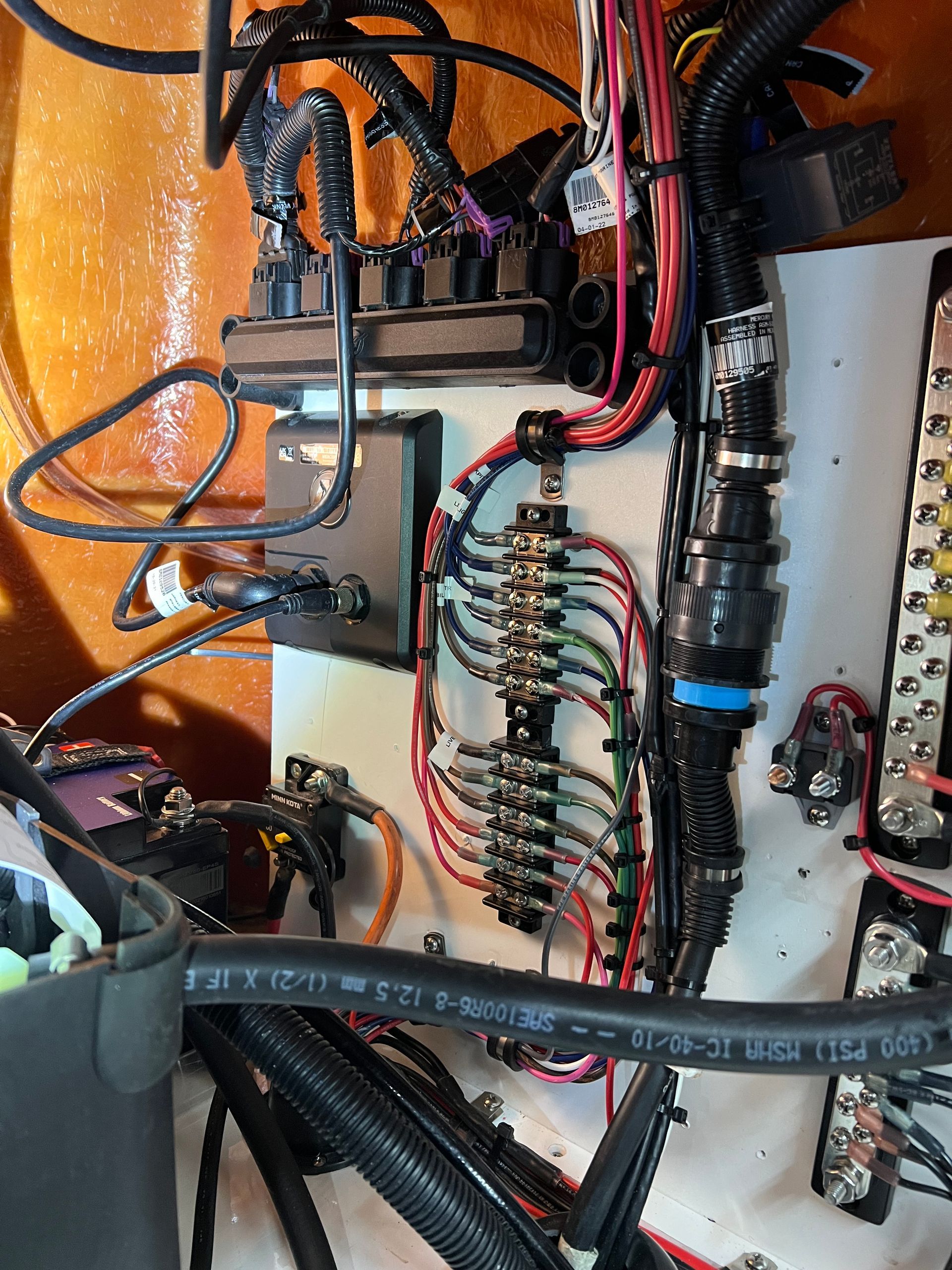 Boat's electrical panel with wires, fuses, and connectors in a compartment.