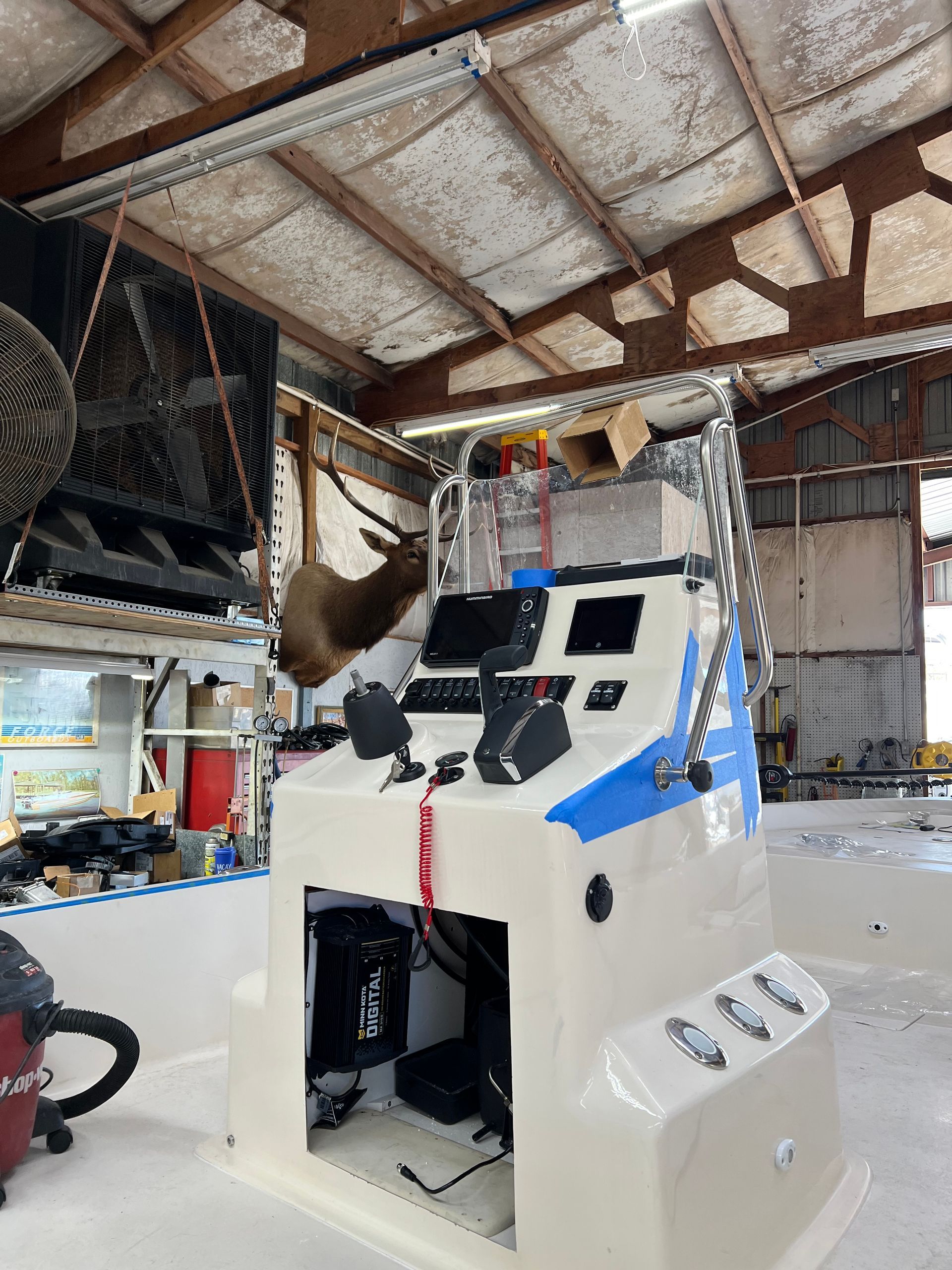 Boat console in a workshop with gauges, steering, and a mounted elk head.