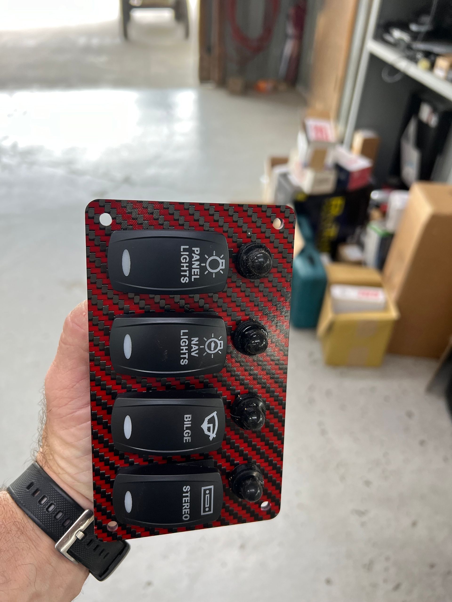 Mechanic in blue overalls inspecting a boat's propeller shaft with a flashlight, tools on mat.