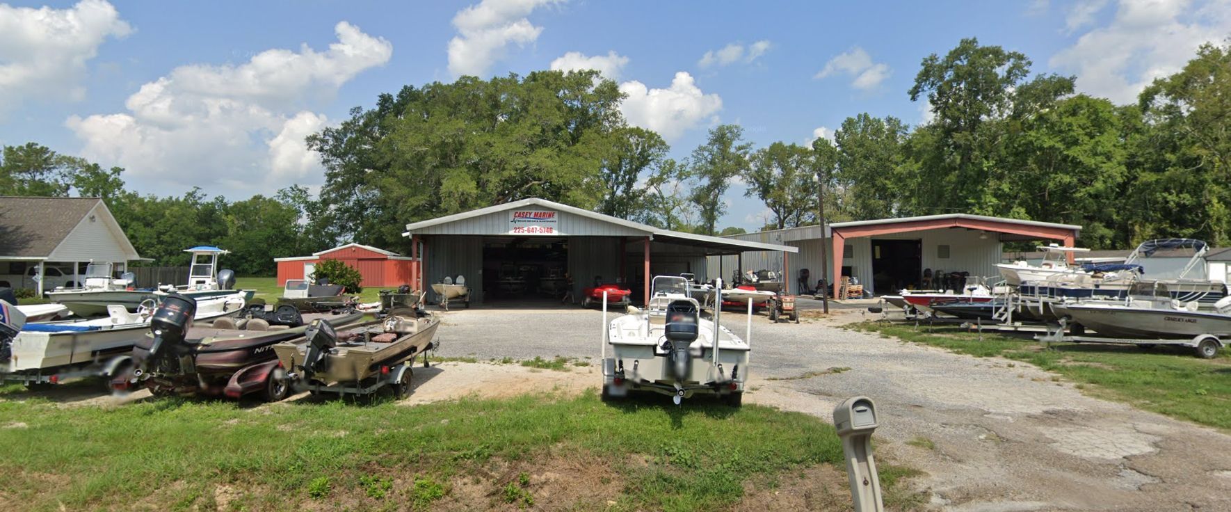 Boats are parked in front of a boat repair shop on a sunny day.