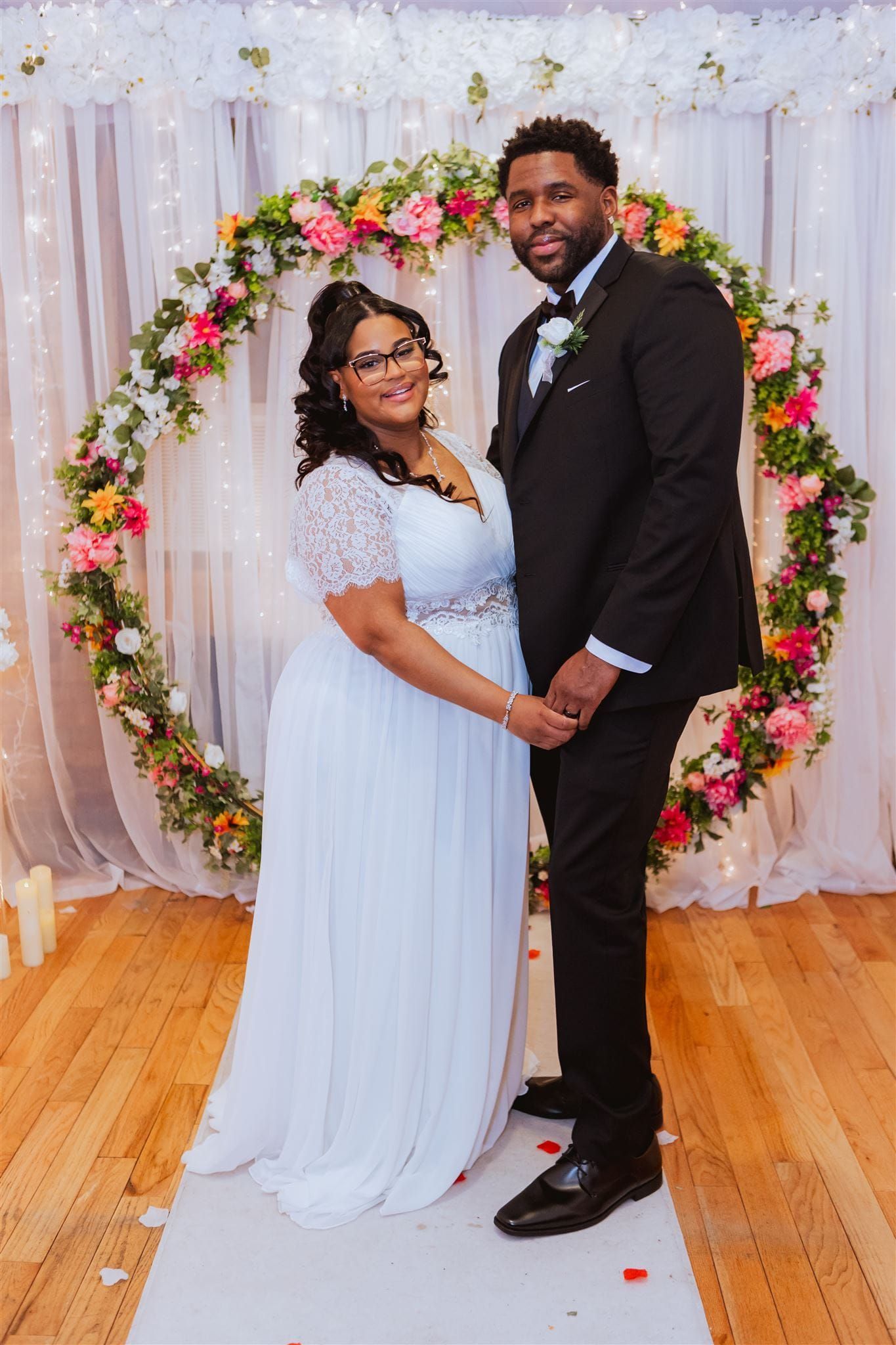 Wedding ceremony: Bride and groom facing officiant, bridesmaids in purple, groomsmen in suits, wooden interior.