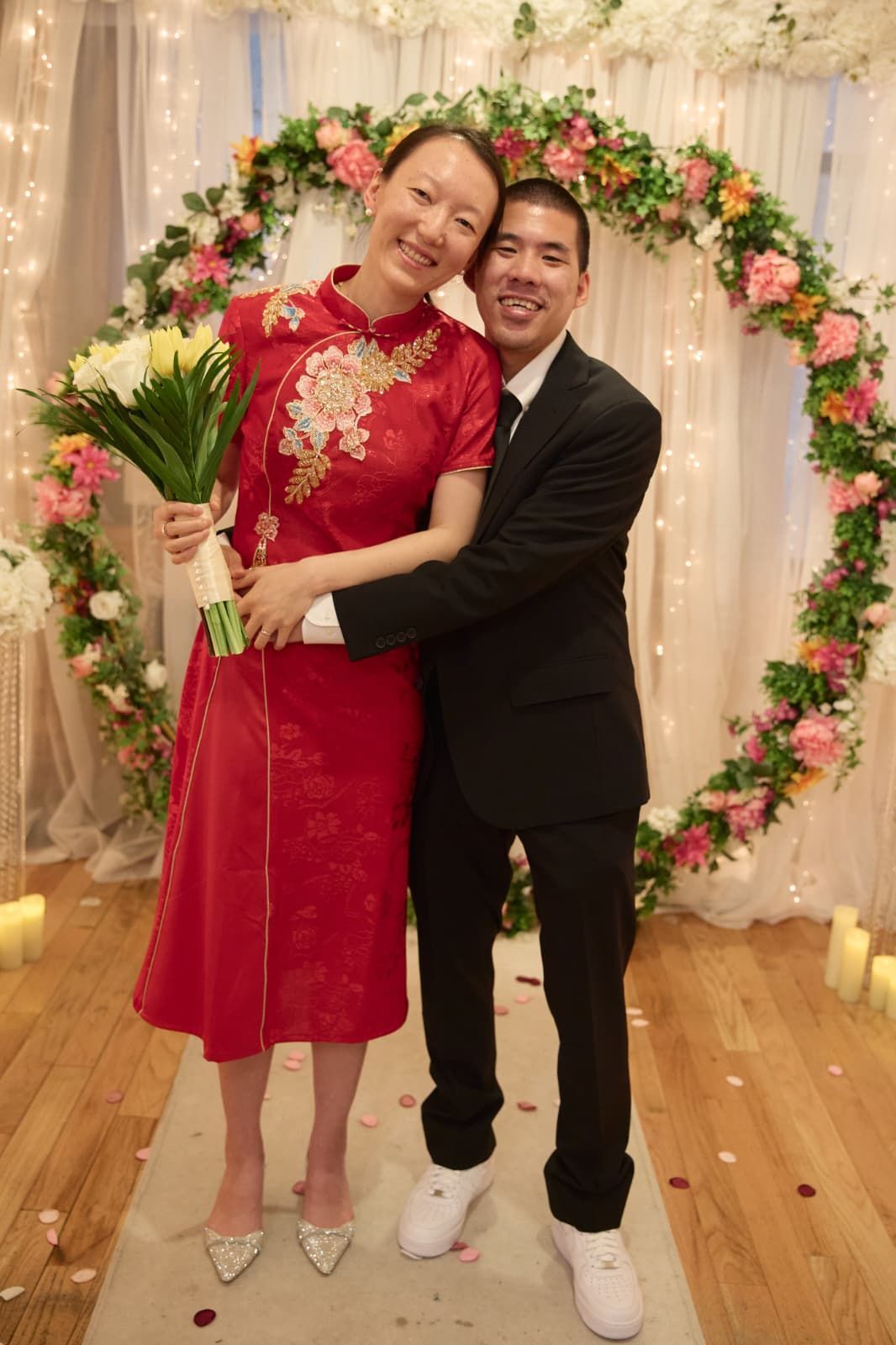 Bride and groom kissing near a bridge, sunny day. Bride in white dress, groom in black suit.