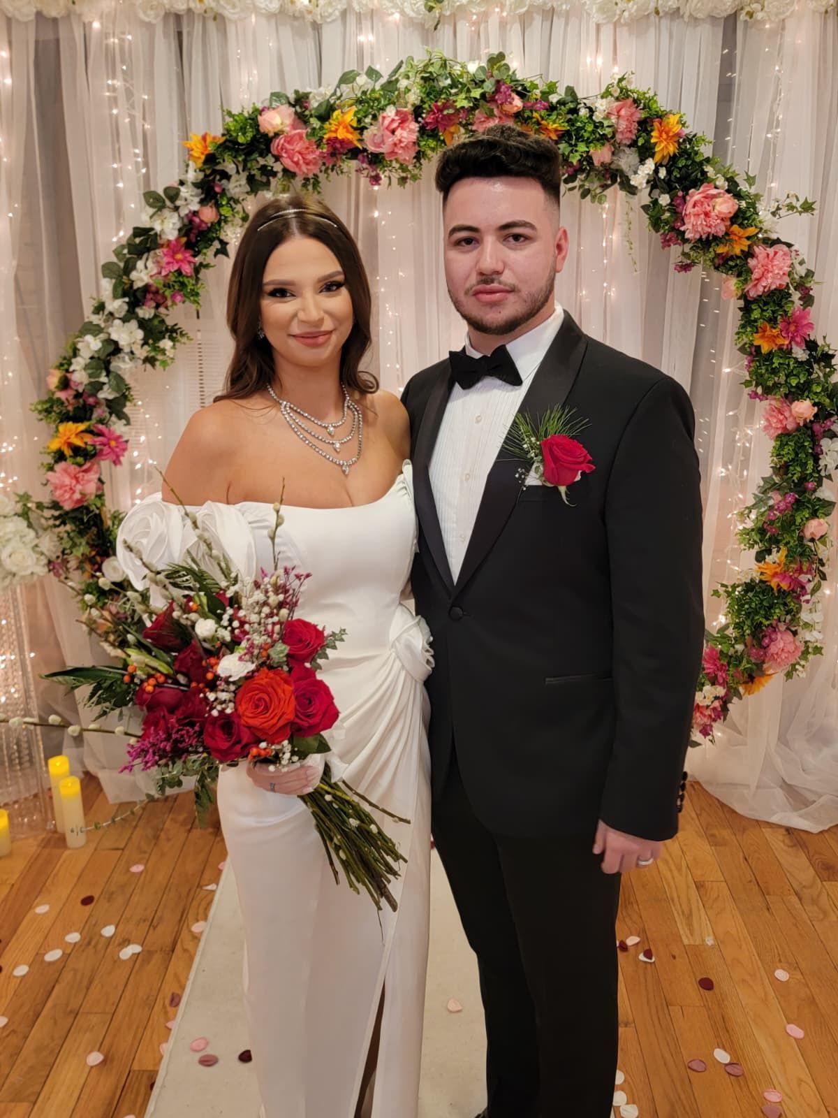 Couple pouring sand into an hourglass during a ceremony. Red dress, white and red accents.