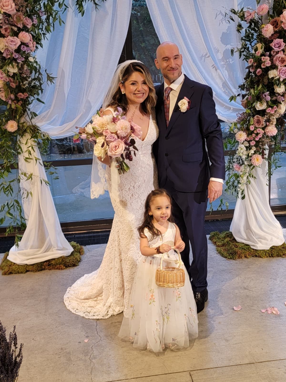 Bride and groom holding hands during outdoor wedding ceremony. Officiant, bridesmaid, and cameraman present.
