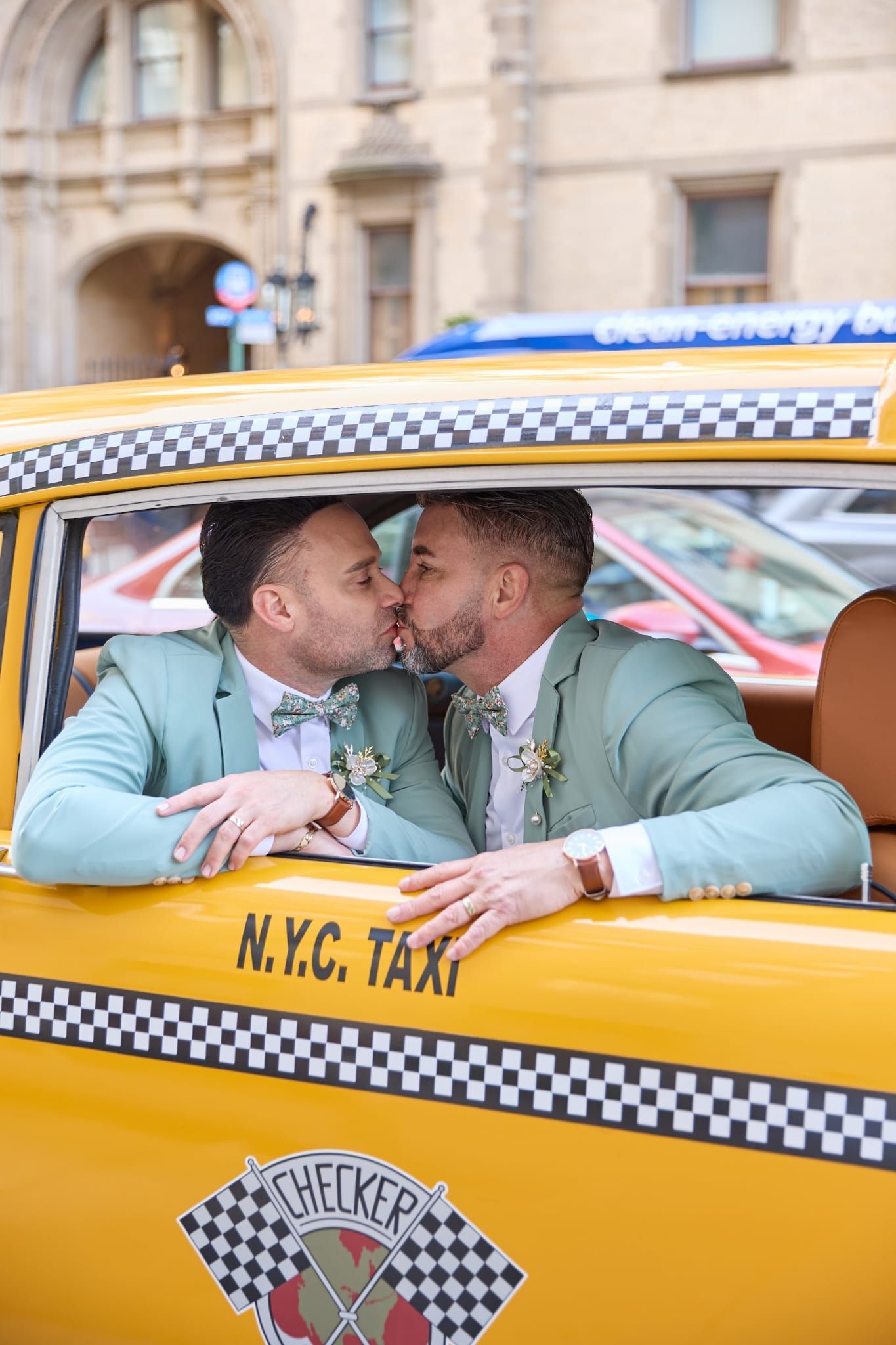 Two people in mint-green suits kiss inside a yellow New York City Checker taxi.