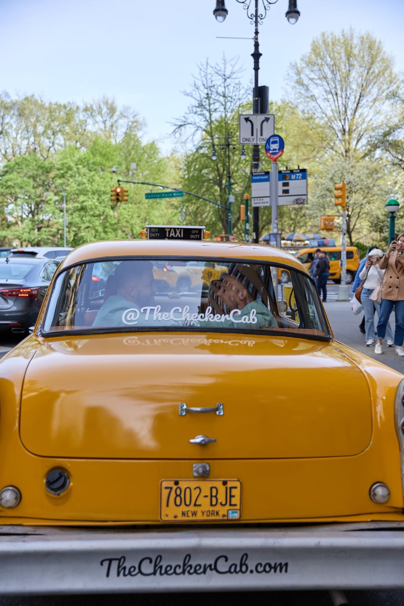 A yellow Checker taxi on a city street, with
