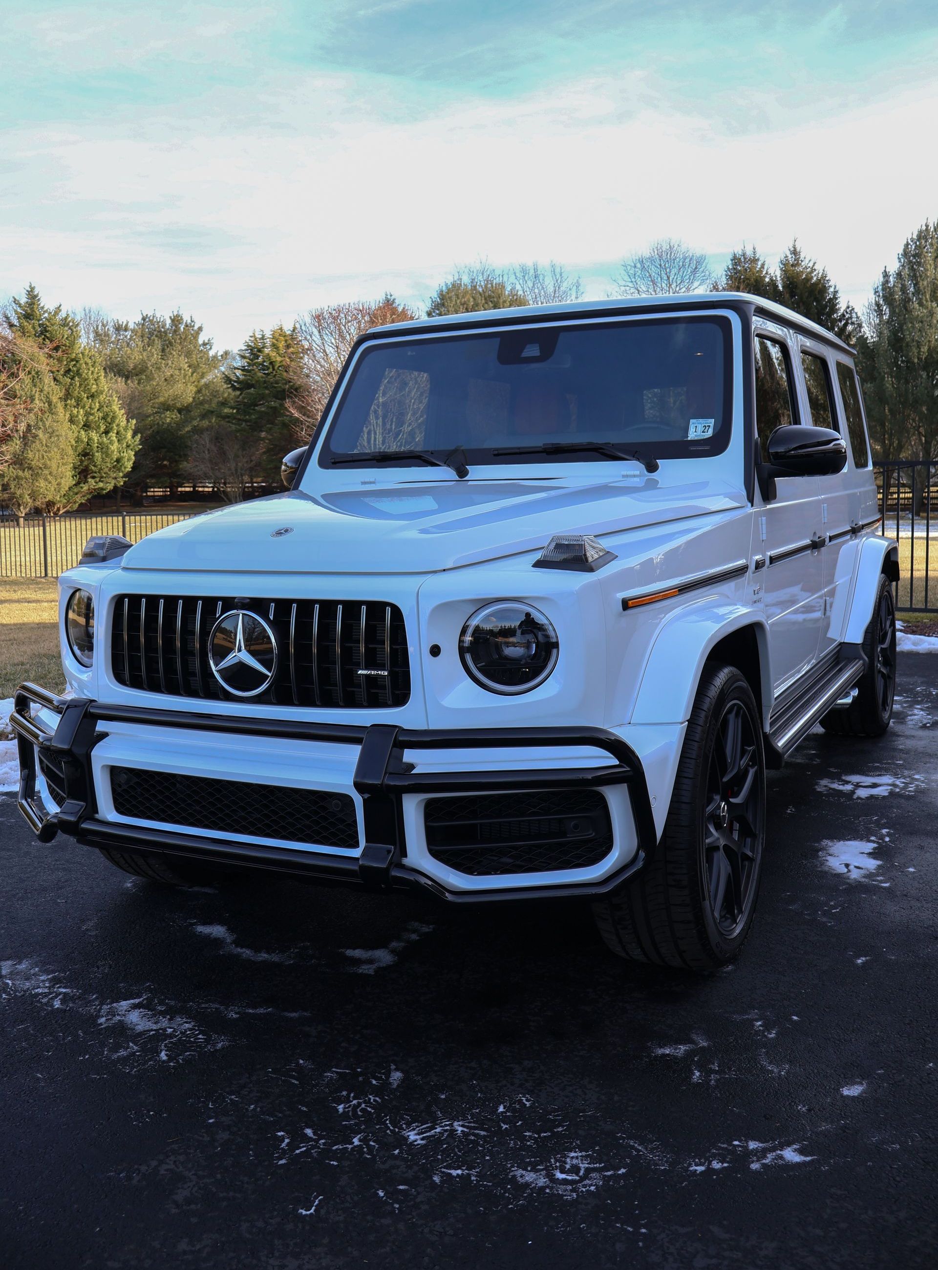 A white mercedes benz g63 amg is parked in a driveway.