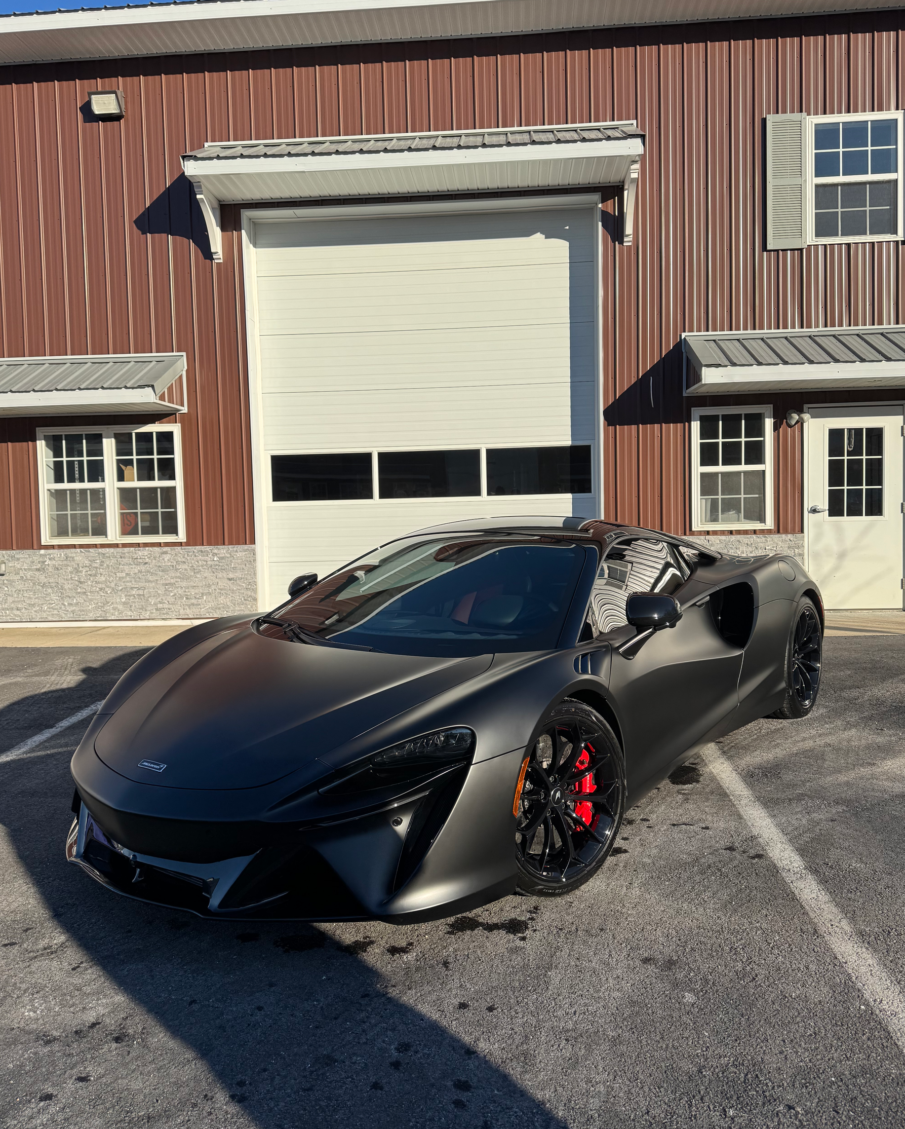 A black sports car is parked in front of a building.