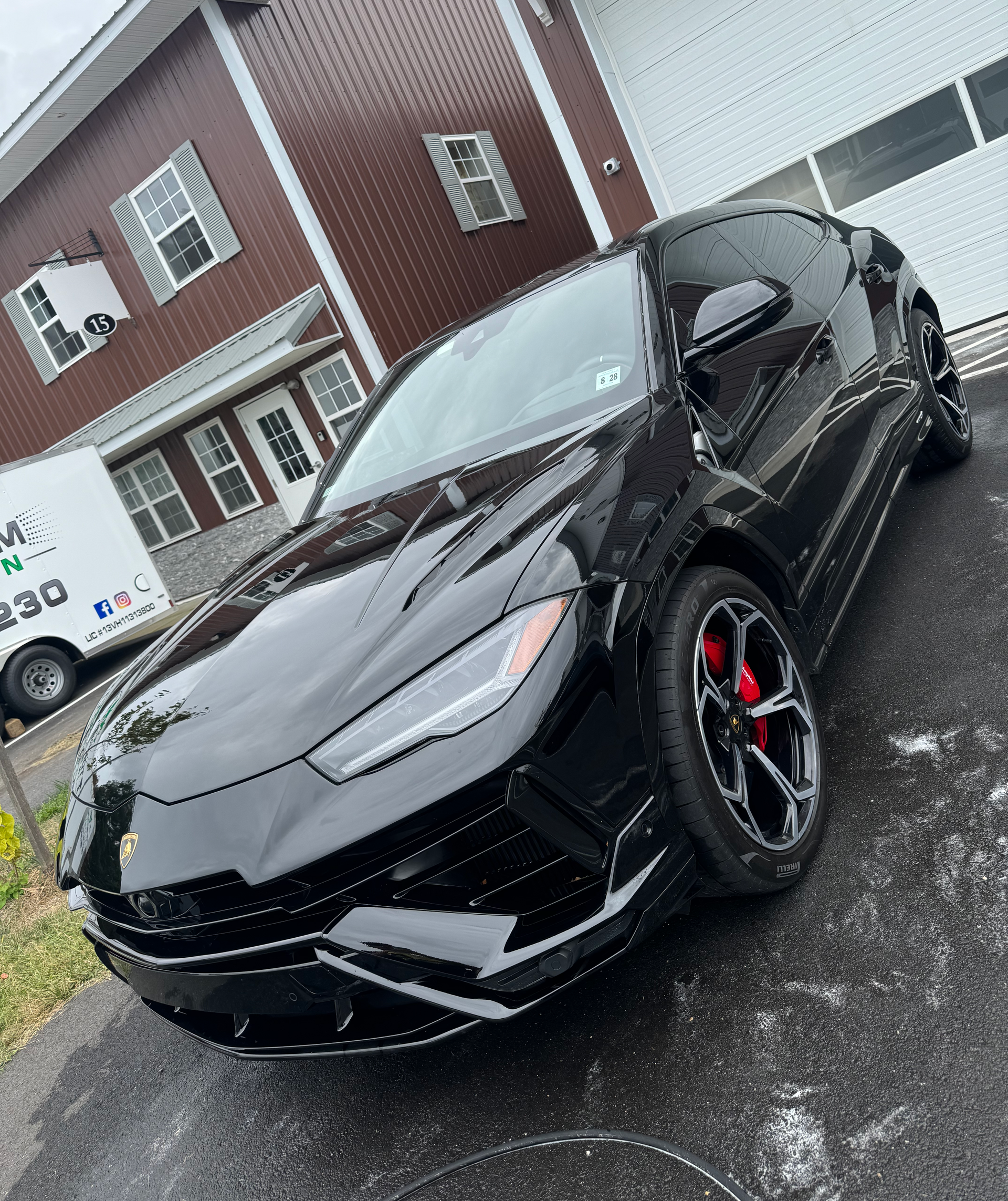 A black Lamborghini Urus is parked in front of a house.