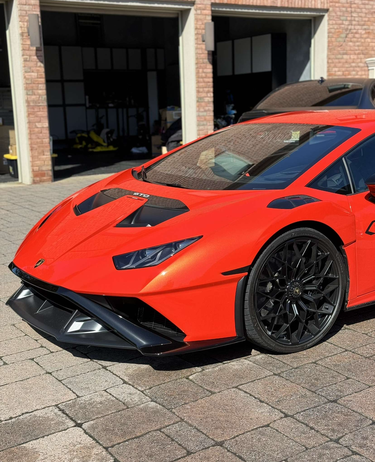 A orange lamborghini huracan is parked in front of a garage.