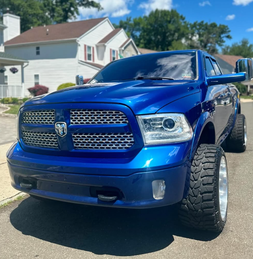 A blue dodge ram truck is parked on the side of the road.