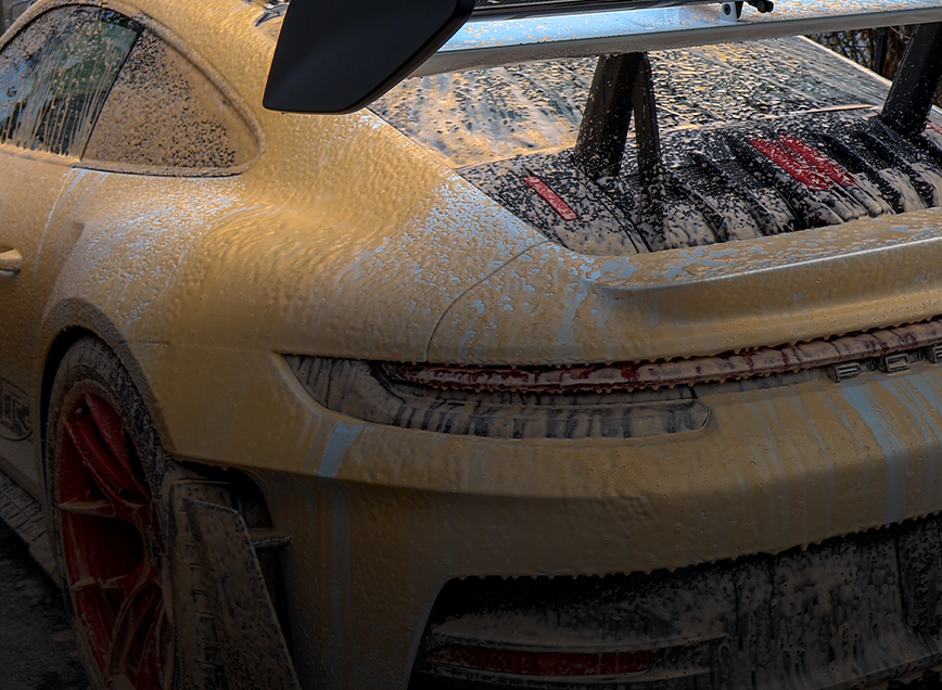 A muddy porsche 911 gt3 is parked on the side of the road.