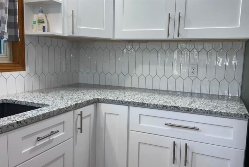 White kitchen corner with gray hex tile backsplash and speckled granite countertops