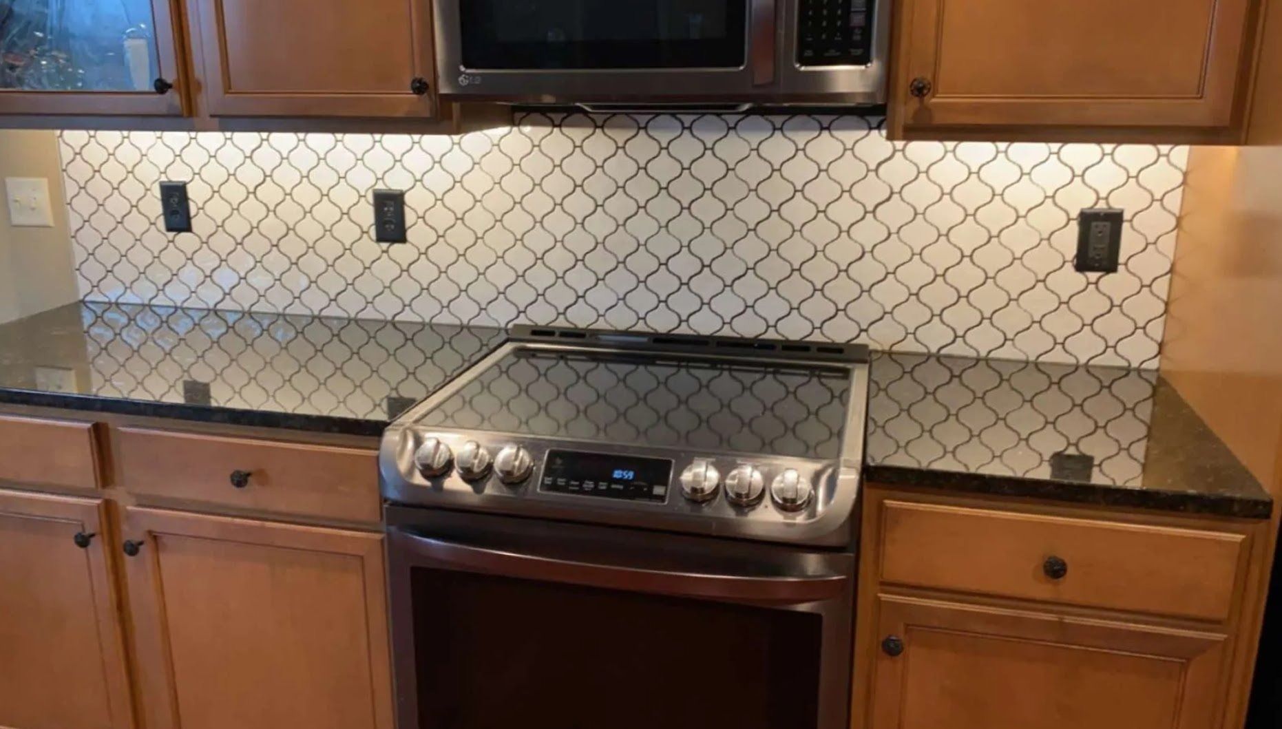 Kitchen with wood cabinets, granite counters, tiled backsplash, and stainless steel electric range.