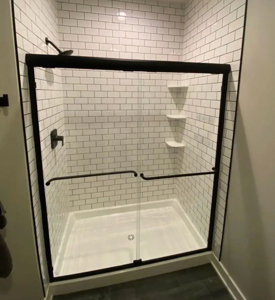 Glass shower enclosure with white subway tile walls and built-in corner shelves.