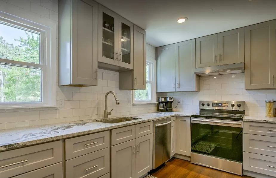 Modern kitchen with gray cabinets, white countertops, and a window over the sink