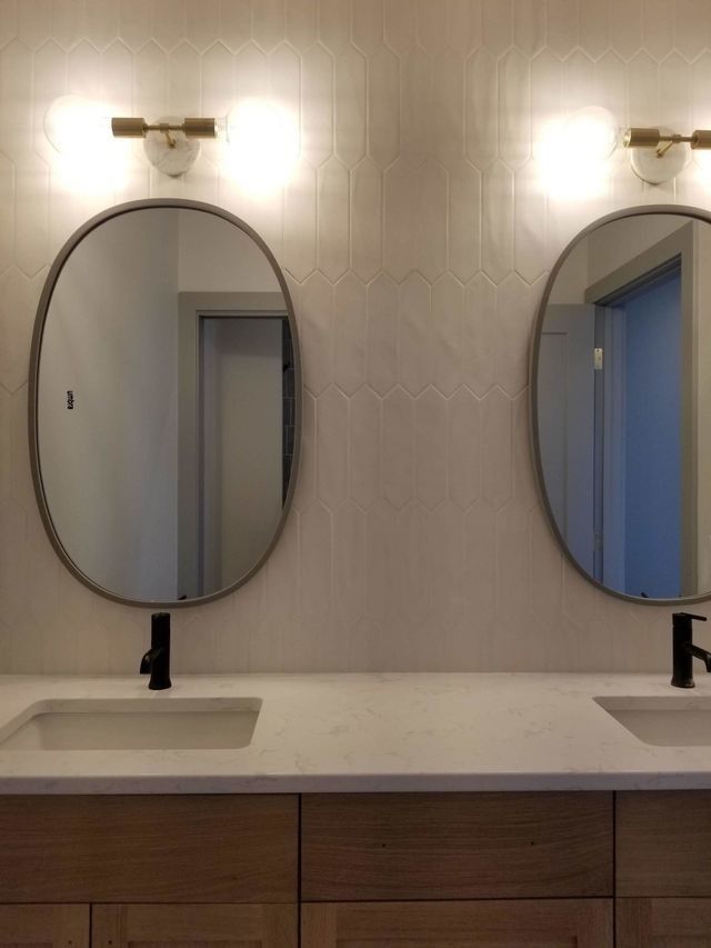 Double sink vanity with oval mirrors and wall sconces in a modern bathroom
