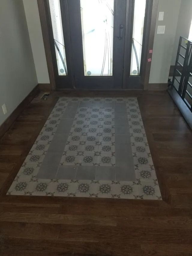 Hallway with dark wood floor and a patterned area rug leading to a glass front door.