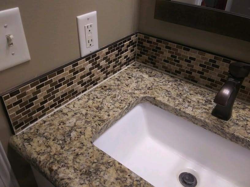 Bathroom sink with speckled granite countertop, mosaic backsplash, and chrome faucet