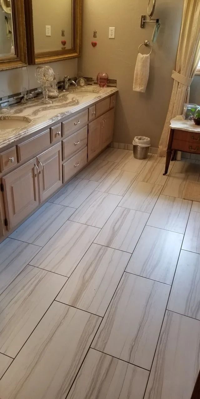 Bathroom with double sink vanity, large mirror, and light tile floor.