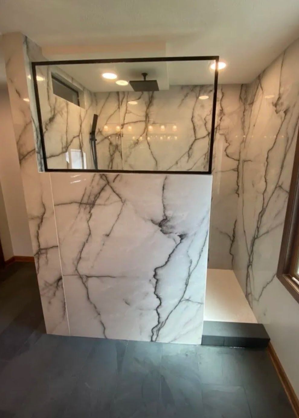 Marble-tiled shower wall with glass enclosure in a modern bathroom