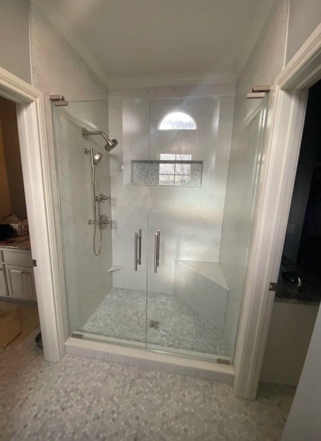 Glass walk-in shower with tiled walls, rain showerhead, and double doors in a bathroom