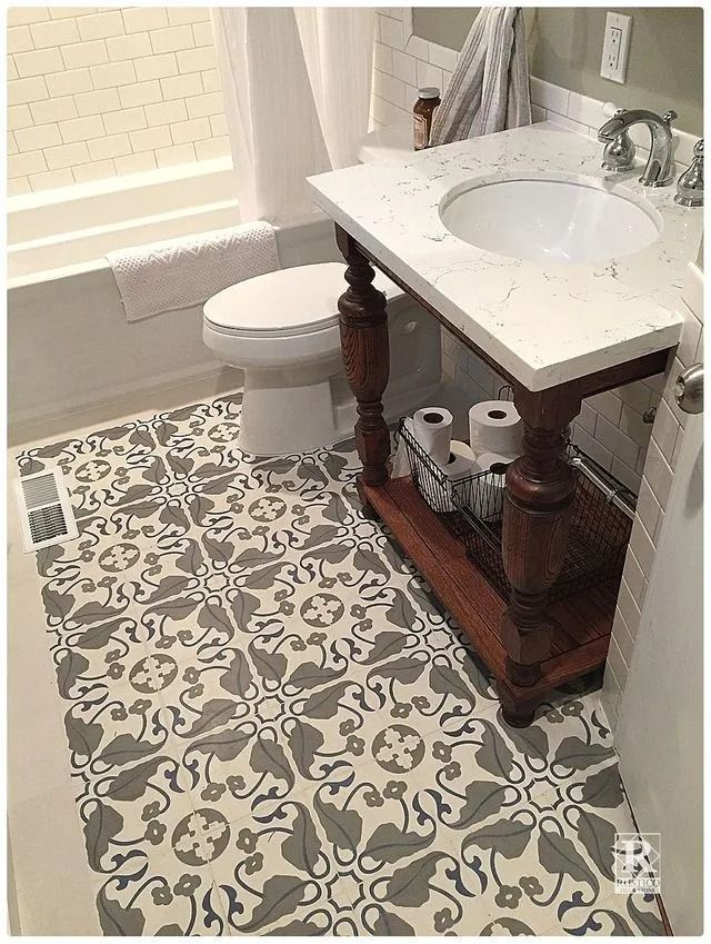 Small bathroom with patterned tile floor, white toilet, vanity sink, and bathtub.