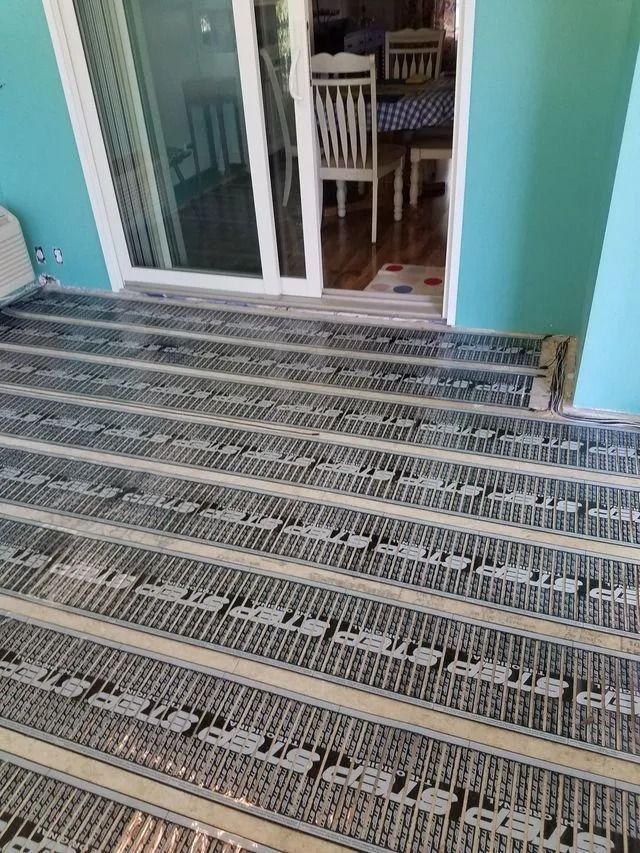 Braided rugs covering a porch floor in front of a sliding glass door and dining area