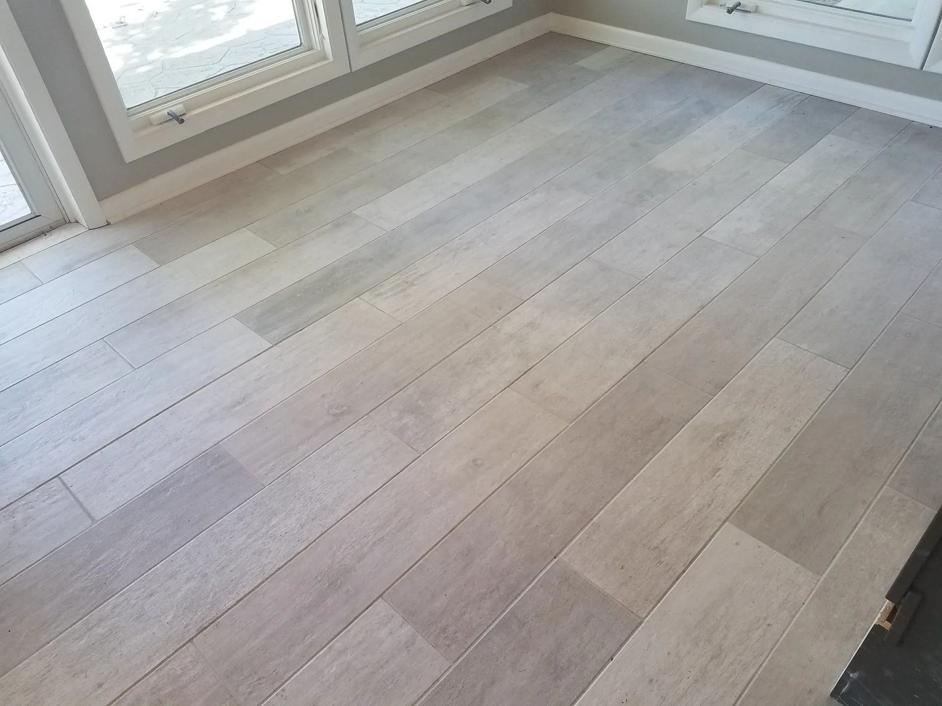 Empty room with light wood flooring and large windows letting in daylight
