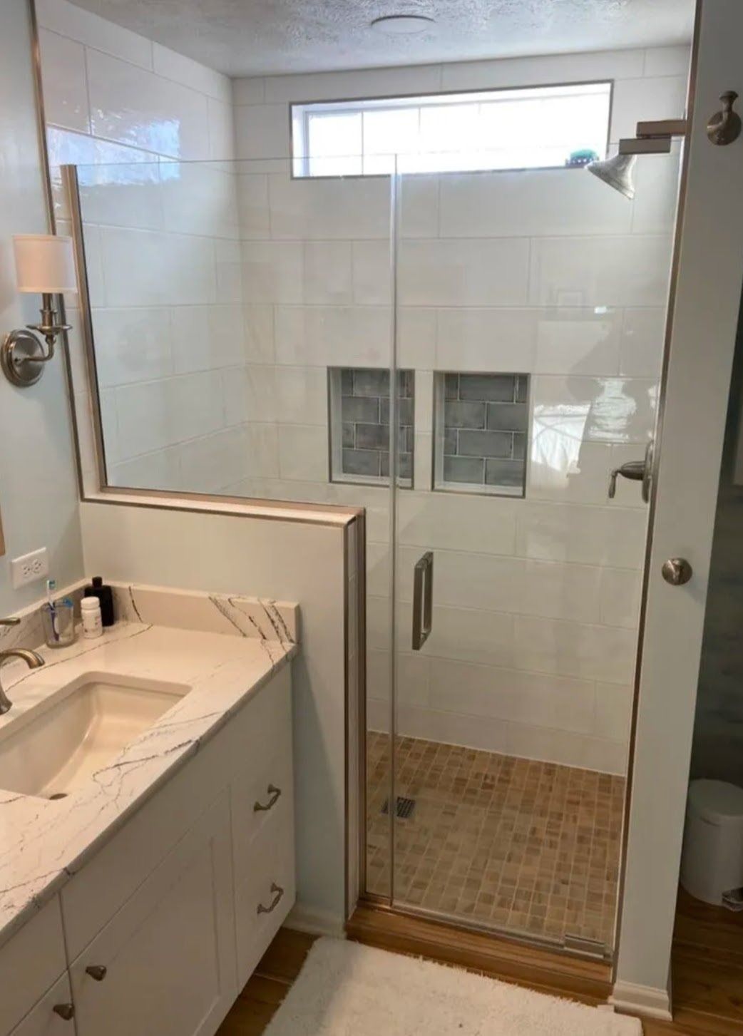 Bathroom with walk-in glass shower, tiled walls, and sink vanity in the foreground