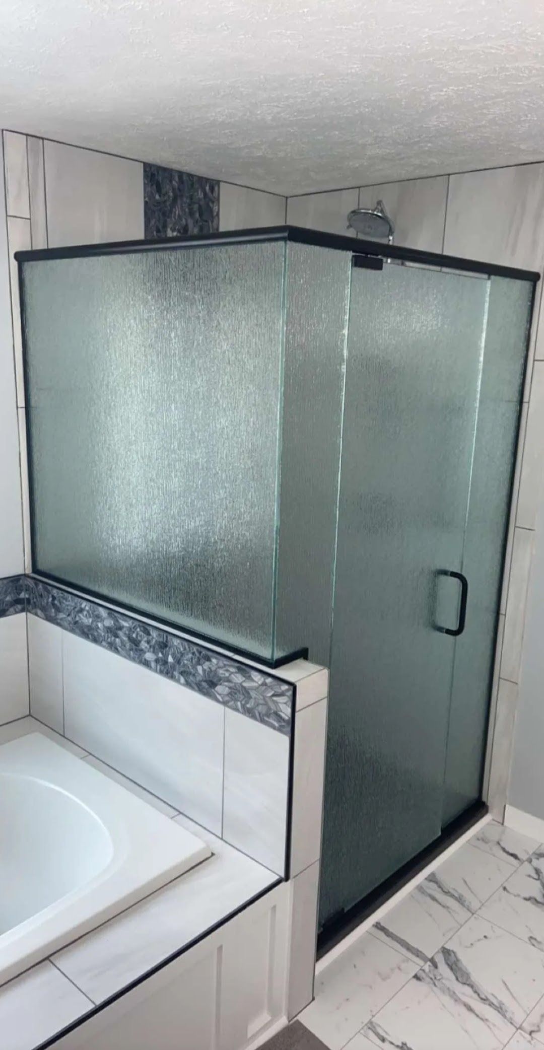 Bathroom with frosted-glass corner shower and white sink vanity in a tiled room