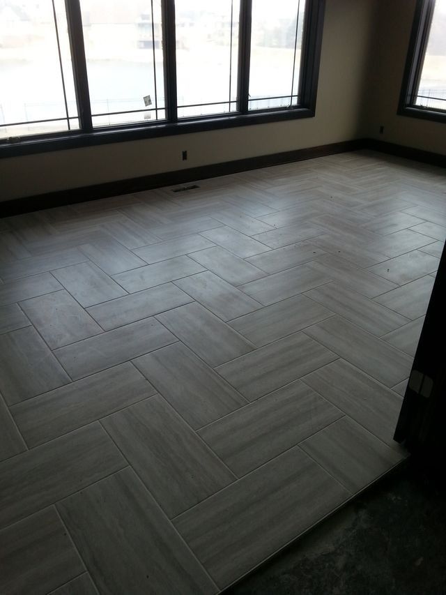 Empty room with light gray herringbone floor and large windows letting in daylight