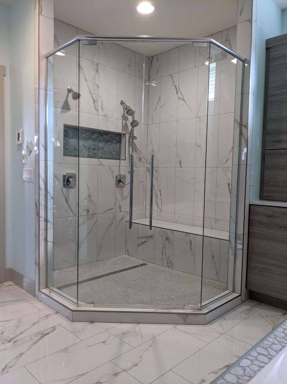 Octagonal glass shower enclosure with marble-like tile in a bathroom