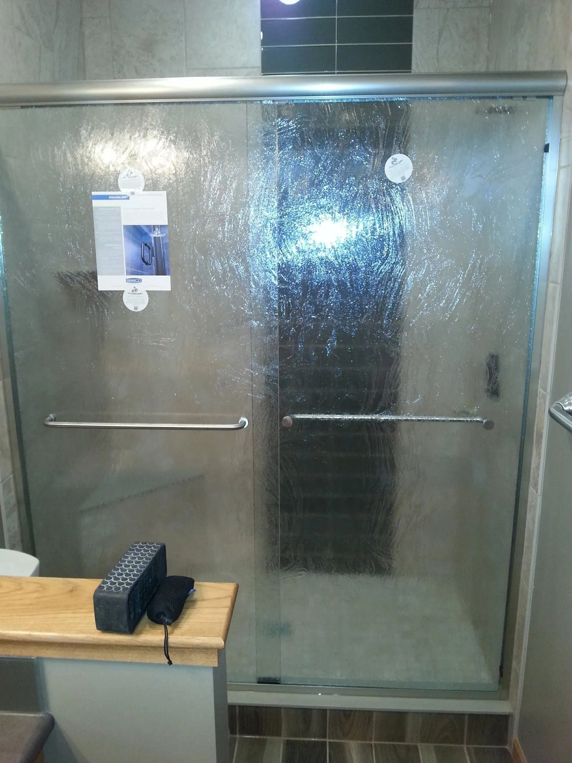 Glass shower stall with frosted doors and a towel rack in a bathroom.