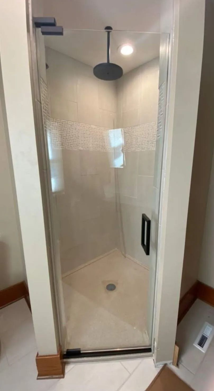 Glass shower stall with white tile walls and a black rain showerhead in a bathroom