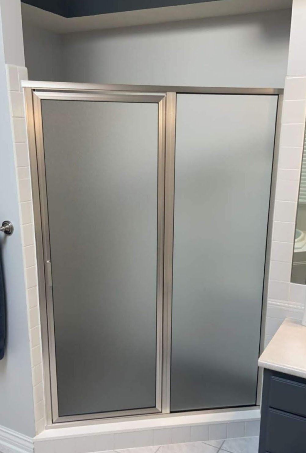 Sliding glass shower door with frosted panels in a bathroom
